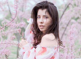 Dziewczyna z ciemnymi włosami stojąca wśród różowych kwiatów