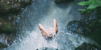 Dziewczyna myjąca włosy pod wodospadem