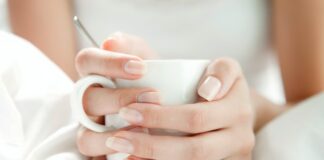 Dziewczyna z pięknymi naturalnymi paznokciami, trzymająca kubek.