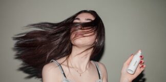 Dziewczyna z ciemnymi, długimi włosami, trzymajaca w ręce kosmetyk do pielęgnacji